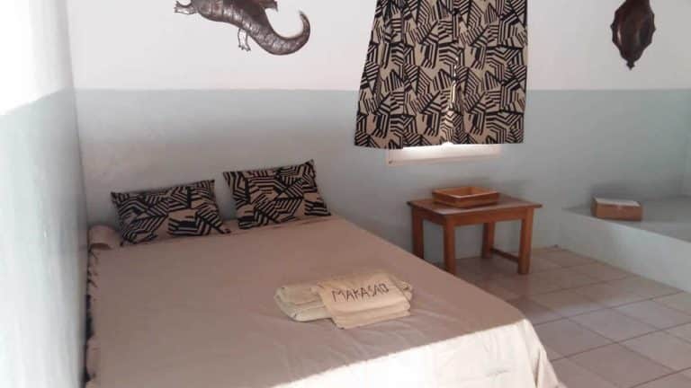 La chambre d’un lodge : lit double, tissus africains et masque au mur