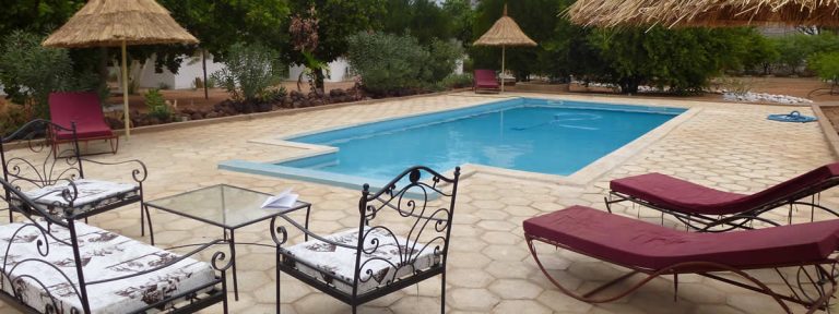 Transats et parasols de paille au bord de la piscine